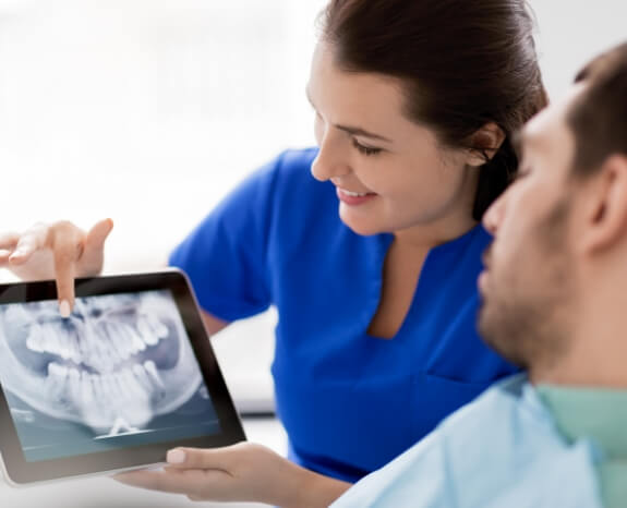Dental patient and dentistry team member looking at digital x rays