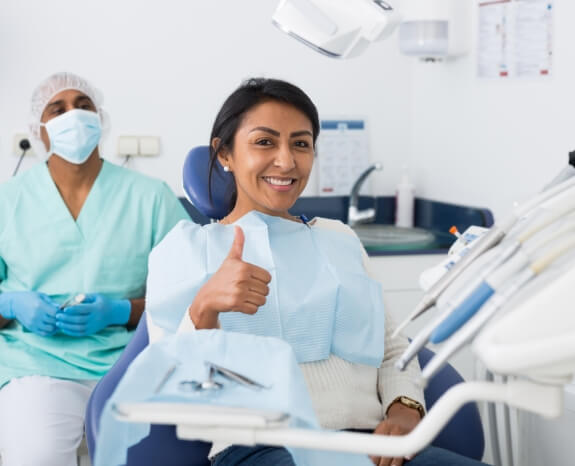 Woman in dental chair giving thumbs up