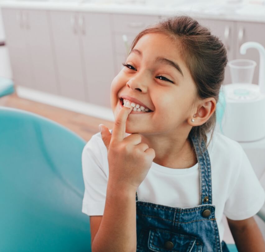Young dental patient pointing at smile during children's dentistry visit