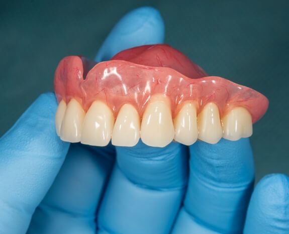 Hand holding a full upper denture