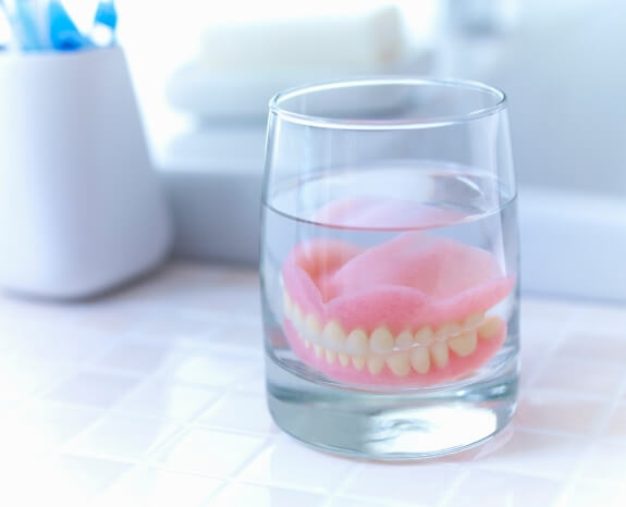 Dentures soaking in glass of water