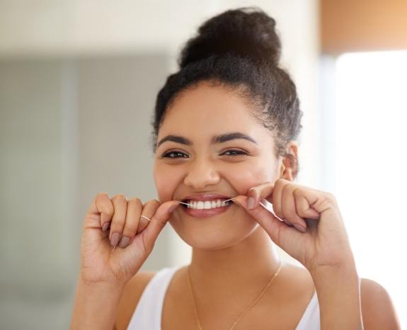 Woman flossing to prevent dental emergencies