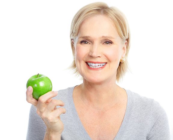 mature woman about to eat green apple 