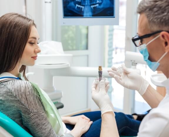 Dentist using mode to explain the dental implant process
