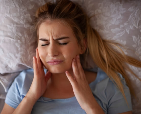 Woman in pain caused by bruxism teeth grinding