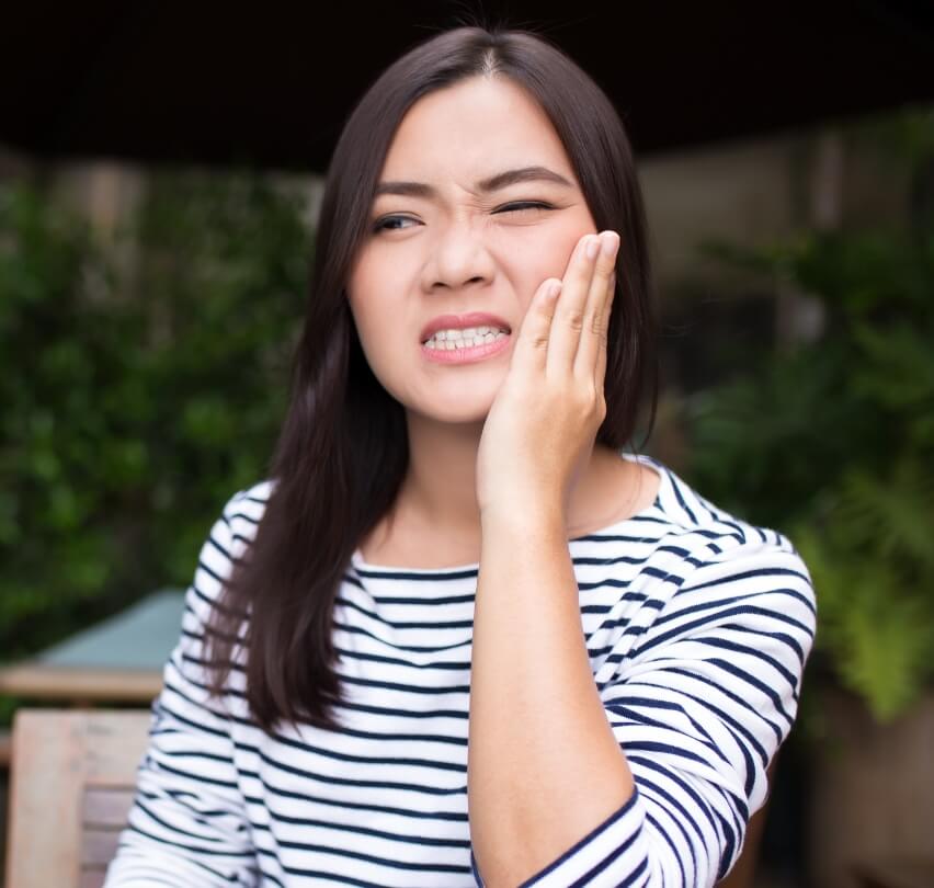 Woman holding cheek before restorative dentistry