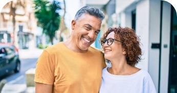 Man and woman smiling after replacing missing teeth