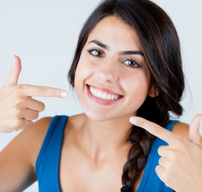 Woman pointing to bright smile after teeth whitening