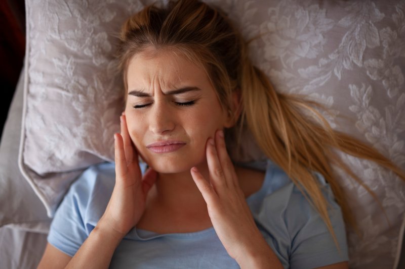 A woman holding her jaw due to TMD